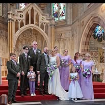 Wedding party posing in a church, dressed in formal attire with lavender accents.